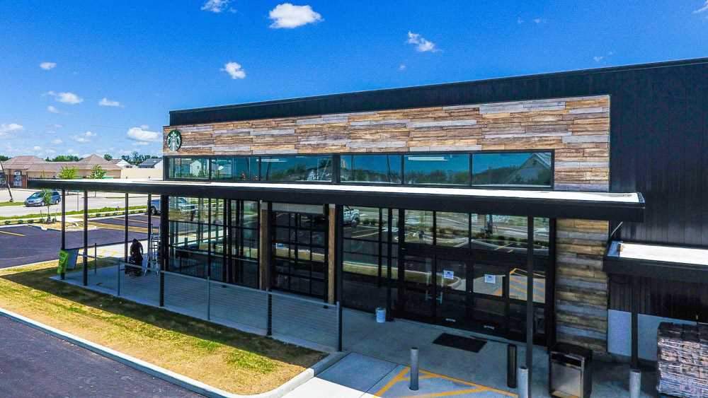 Retail storefront with URESTONE reclaimed faux wood siding band above glazing; modern commercial facade.