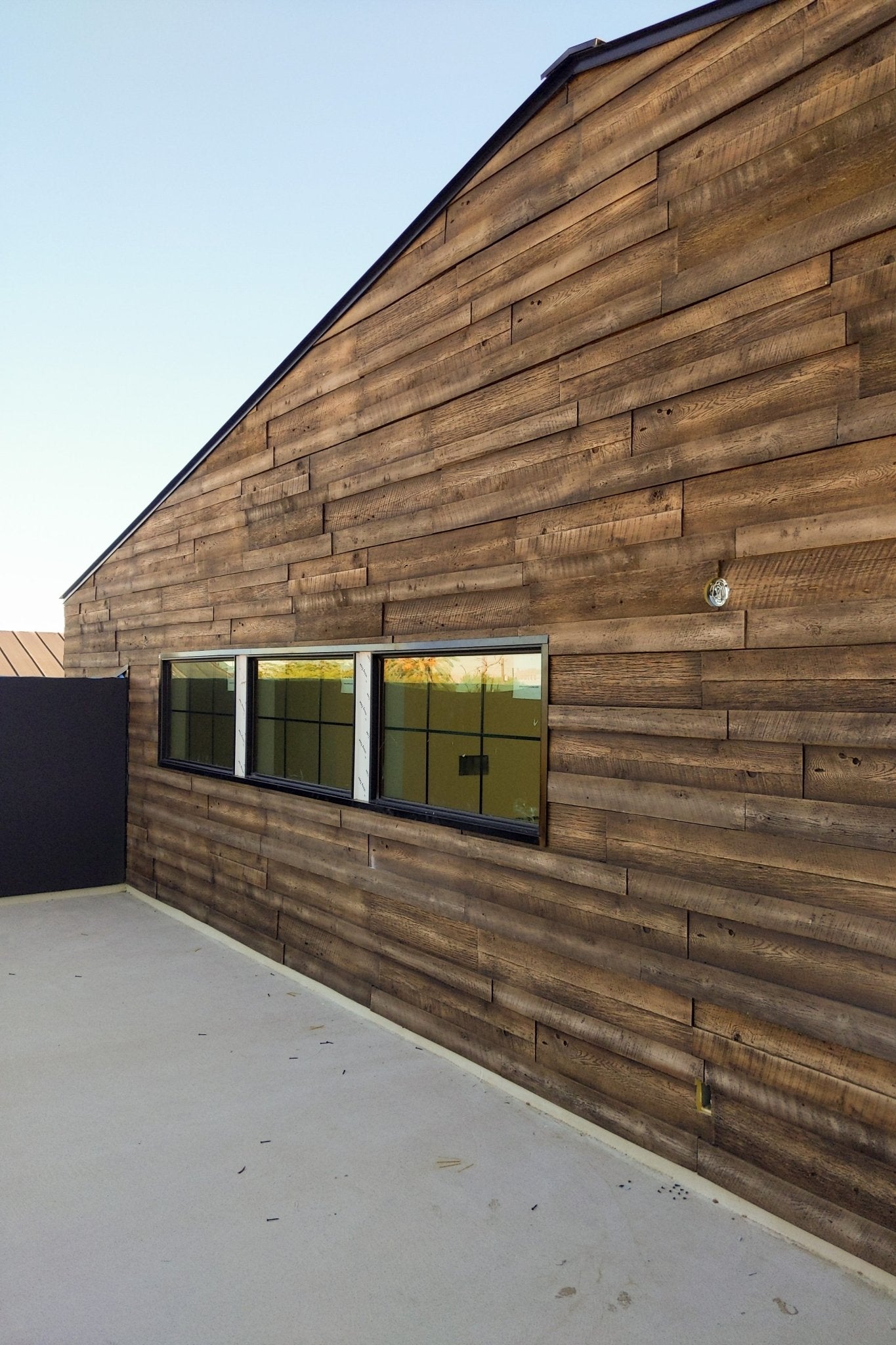 Side elevation showing URESTONE reclaimed faux wood panels, staggered planks, deep grain, modern barn look.