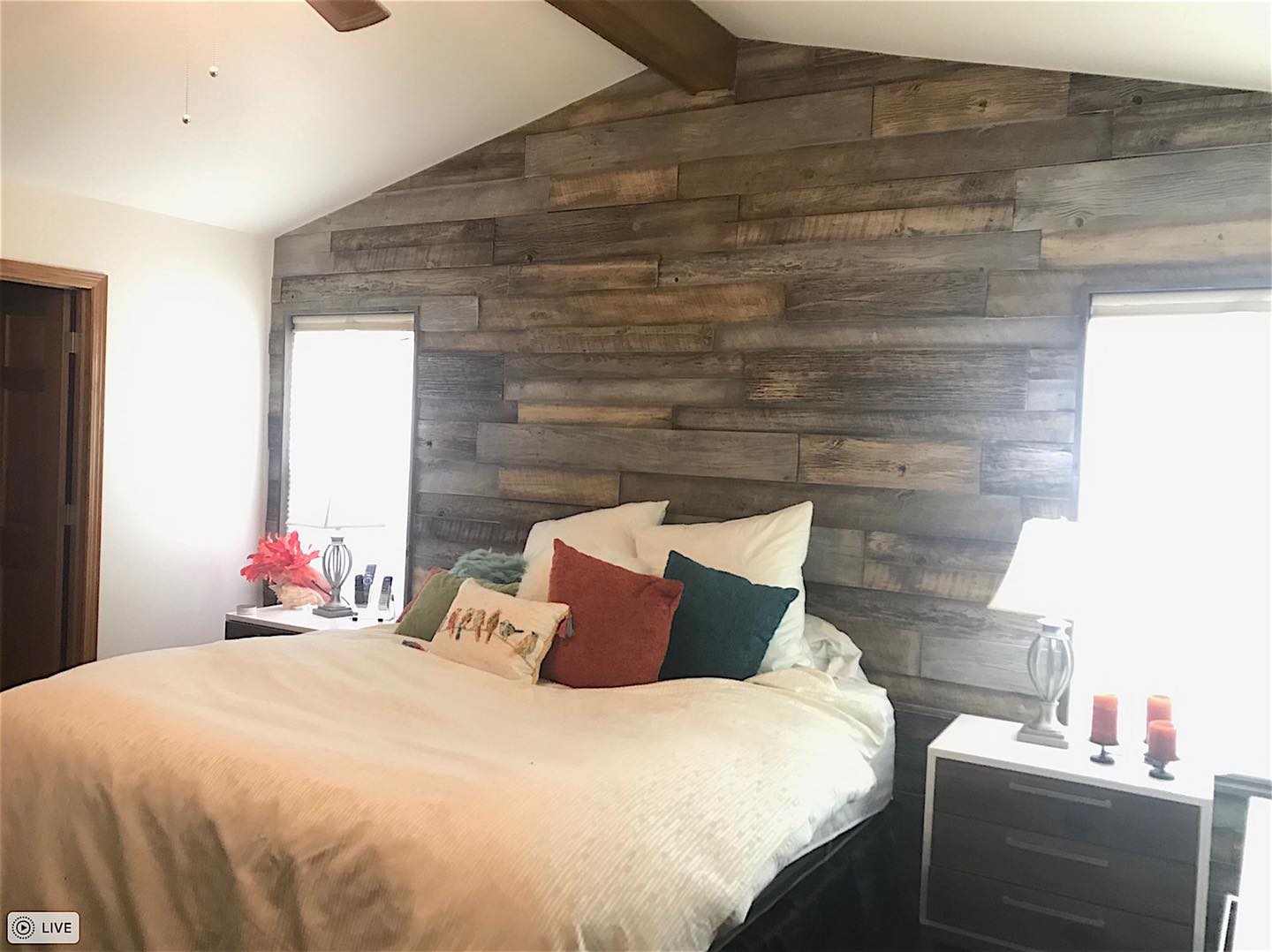 Bedroom feature wall in URESTONE reclaimed faux wood panels, driftwood gray tones, layered planks behind bed.