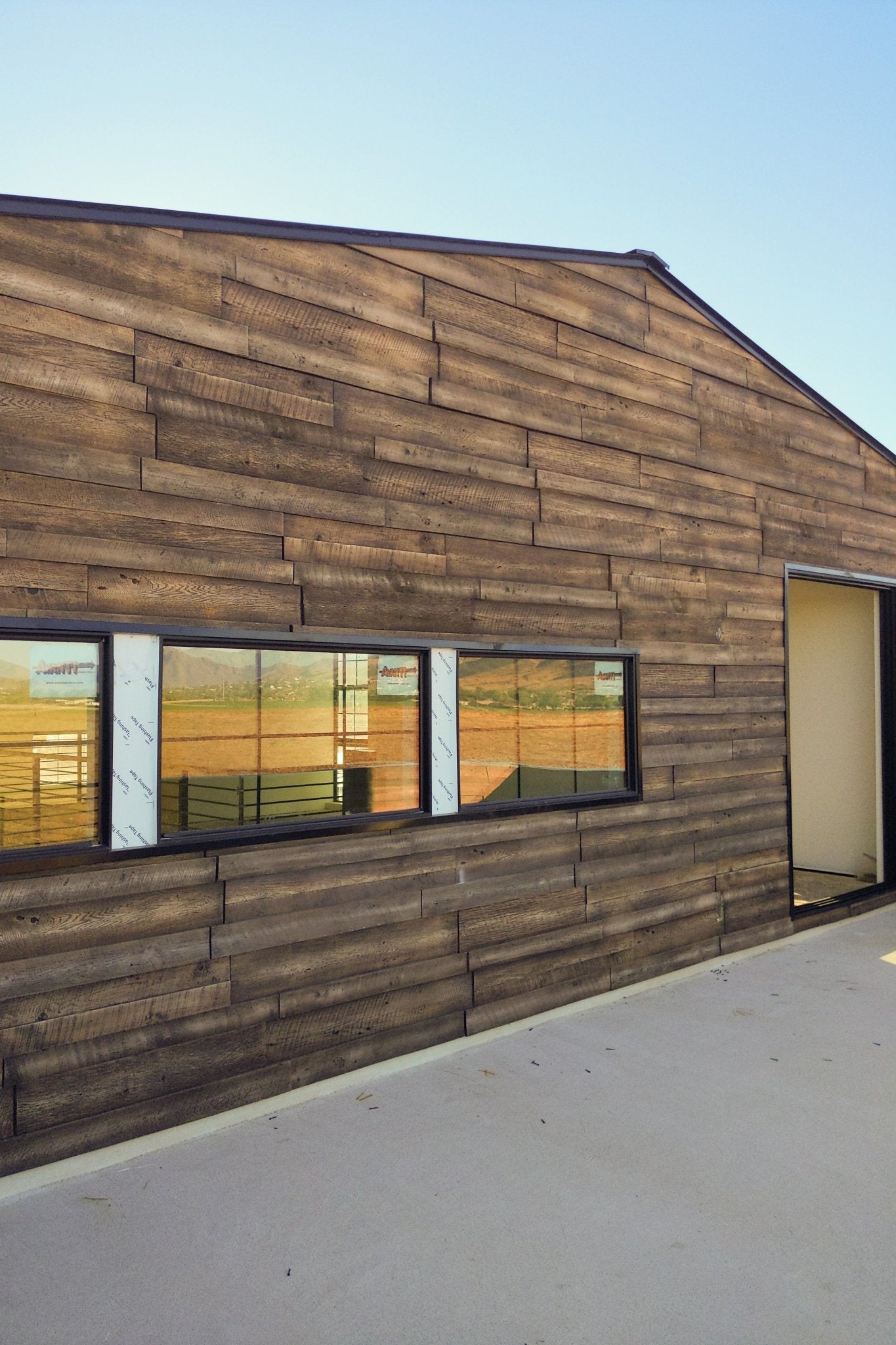 Gable facade with URESTONE reclaimed faux wood siding, long horizontal windows, rustic plank texture.