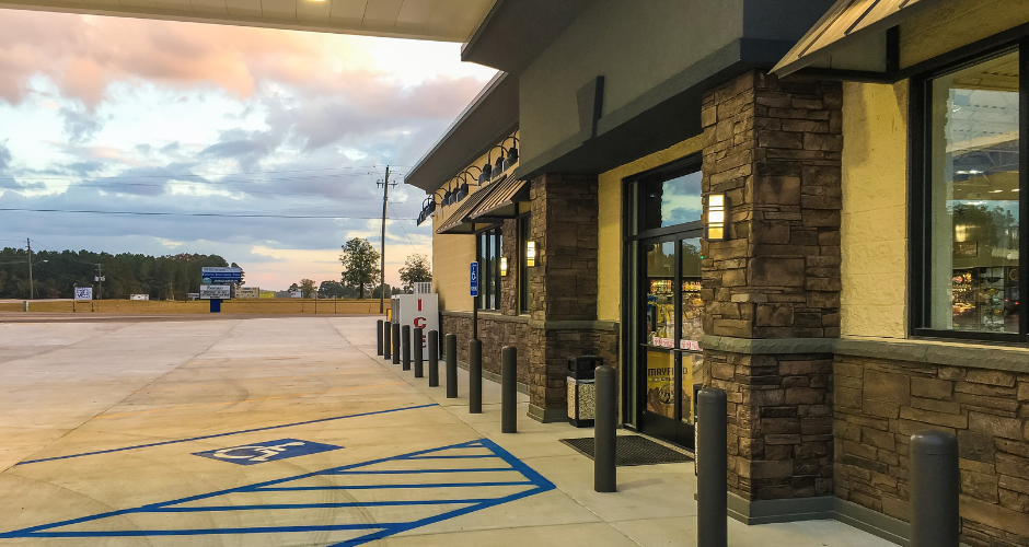 Building exterior with fieldstone ledgestone wainscot and matching pilasters with a parking lot and cloudy sky